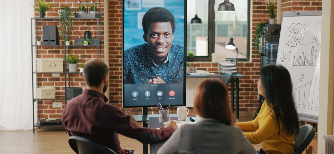 Group of workers using remote video call to talk to man